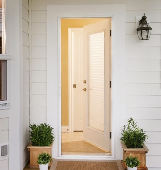 White storm door with glass installed in the front of a white home